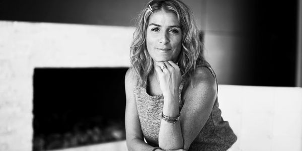 Black and white portrait of a thoughtful woman sitting indoors.