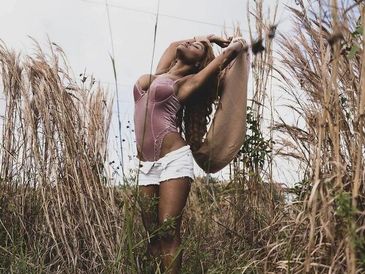 Woman stretching with scarf in tall grass field.