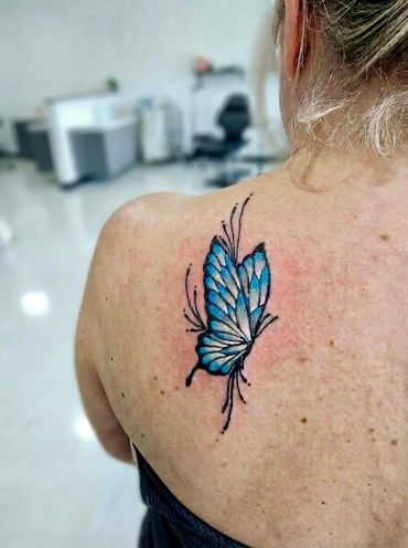 Blue butterfly tattoo on shoulder.