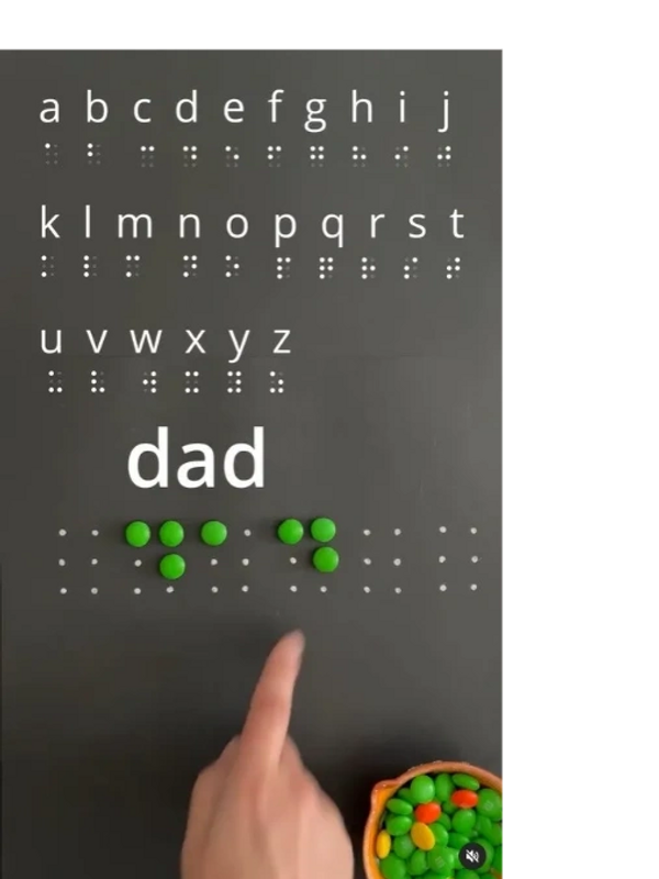 Print and SimBraille of the alphabet and in green M&Ms it says, "dad" in SimBraille. 