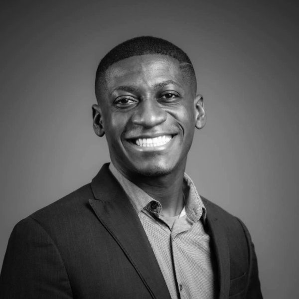 Portrait of a smiling man in a suit against a plain background.