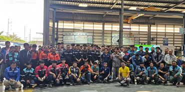 Large group of industrial workers posing for a group photo indoors.