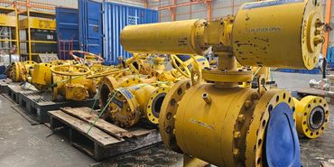 Industrial yellow valves stored on pallets in a warehouse.