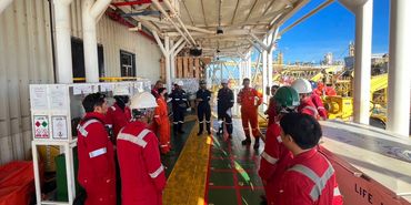 Workers in safety gear having a meeting on an industrial platform.