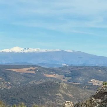 Montañas con cumbres nevadas bajo un cielo azul claro.
