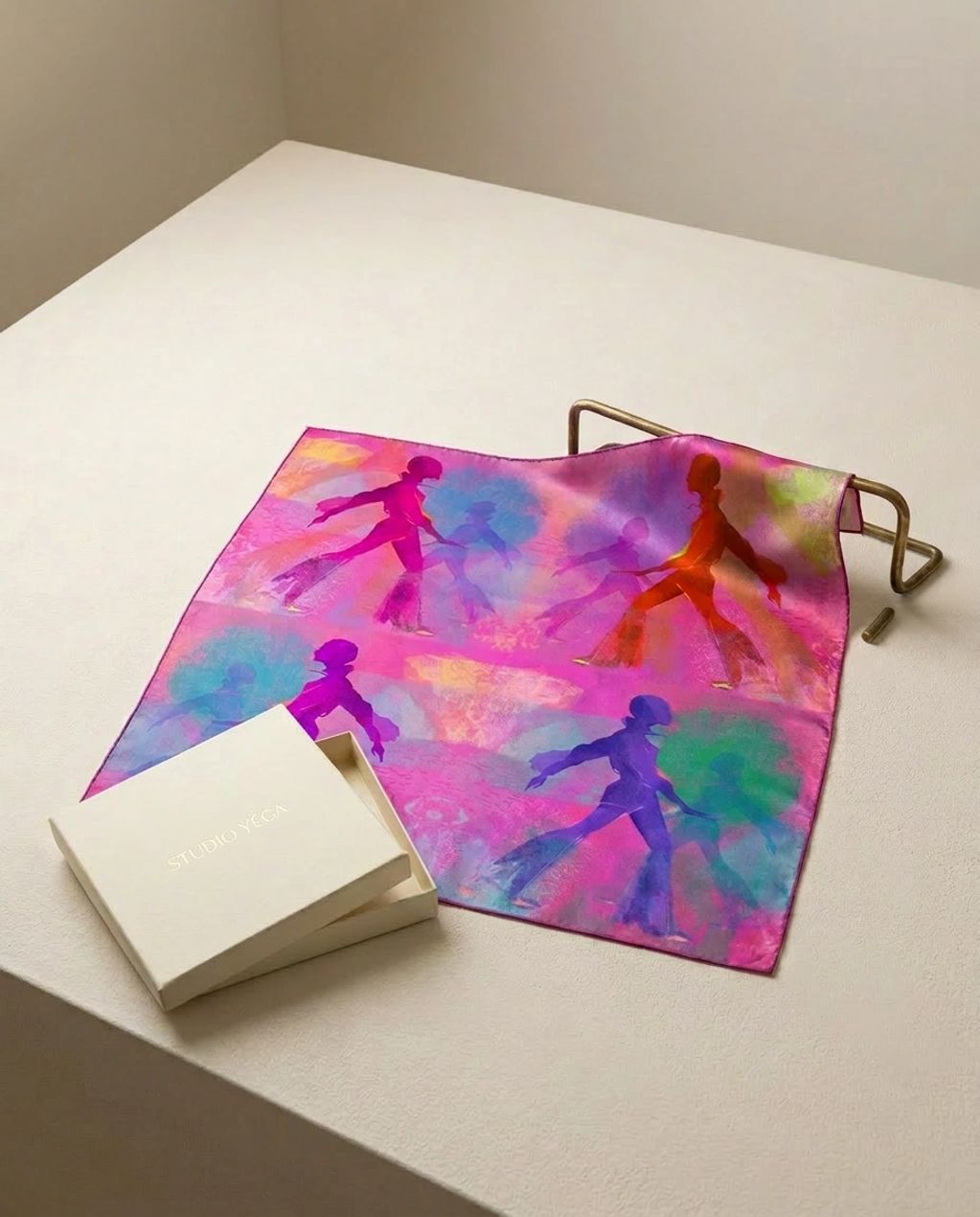 Colorful scarf with abstract dancing figures beside a Studio Yega box.