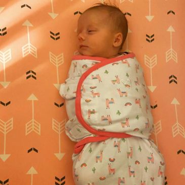 Sleeping baby swaddled in a patterned blanket.