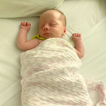 Sleeping baby wrapped in blanket on bed.