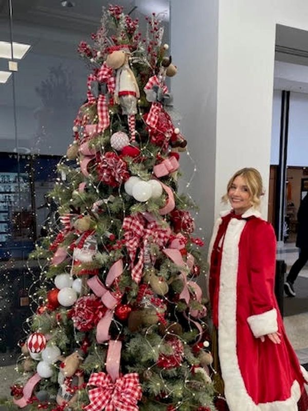 Sapin de Noël décoré avec une femme en manteau rouge.