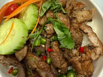 Grilled pork with rice, fresh cucumber, carrot, cherry tomato, and herbs.