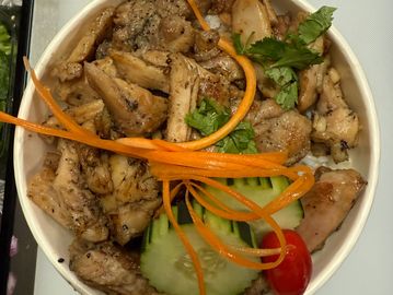 Grilled chicken bowl with rice, cucumber, carrot, and cherry tomato garnish.