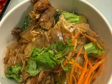 Stir-fried noodles with chicken, broccoli, carrots, and fresh cilantro.