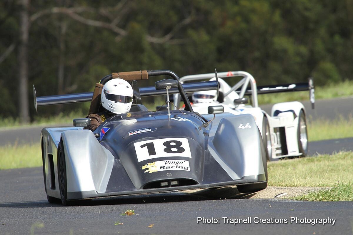 Two race cars with drivers in helmets on a track.