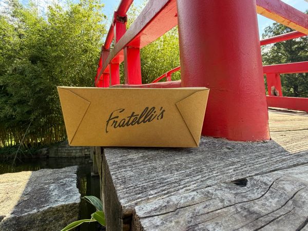 Fratellis catering box on a red wooden bridge near water and greenery.