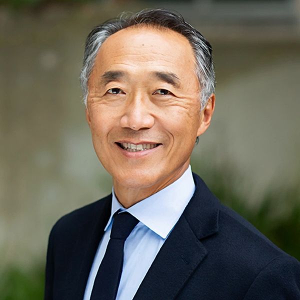 Smiling mature man in a suit and tie posing outdoors.