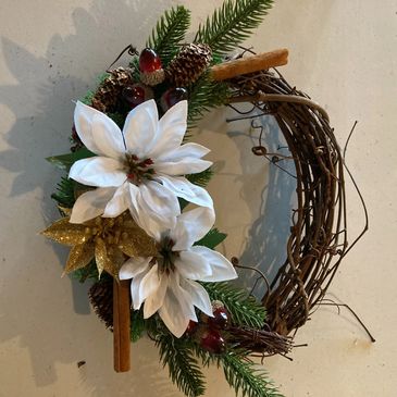 A Christmas wreath featuring white and gold flowers and greenery.