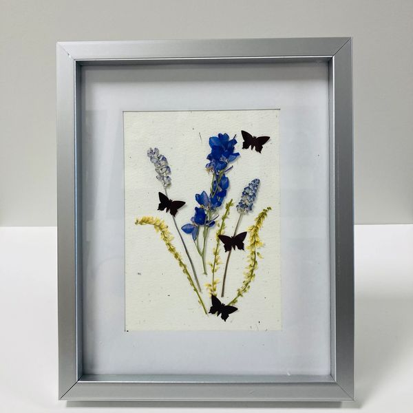 A pressed flower piece featuring butterflies and pressed flowers.