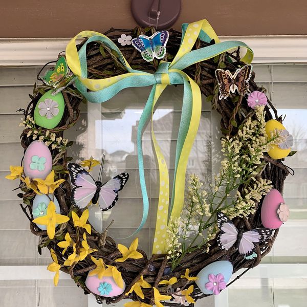 A spring wreath decorated with ribbon, eggs, butterflies and flowers.