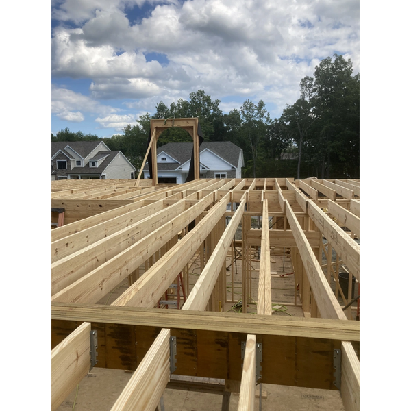 Wooden framework of a house under construction on a partly cloudy day.