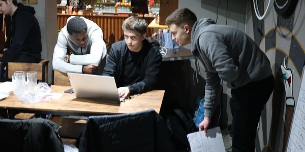 Three young men collaborating over a laptop in a casual workspace.
