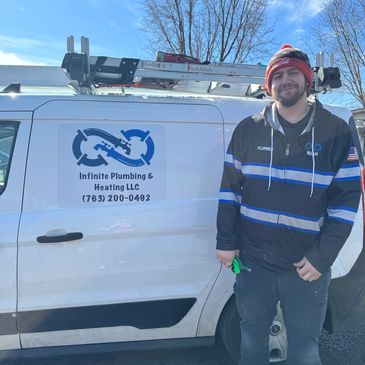 Plumber standing next to company van with logo.