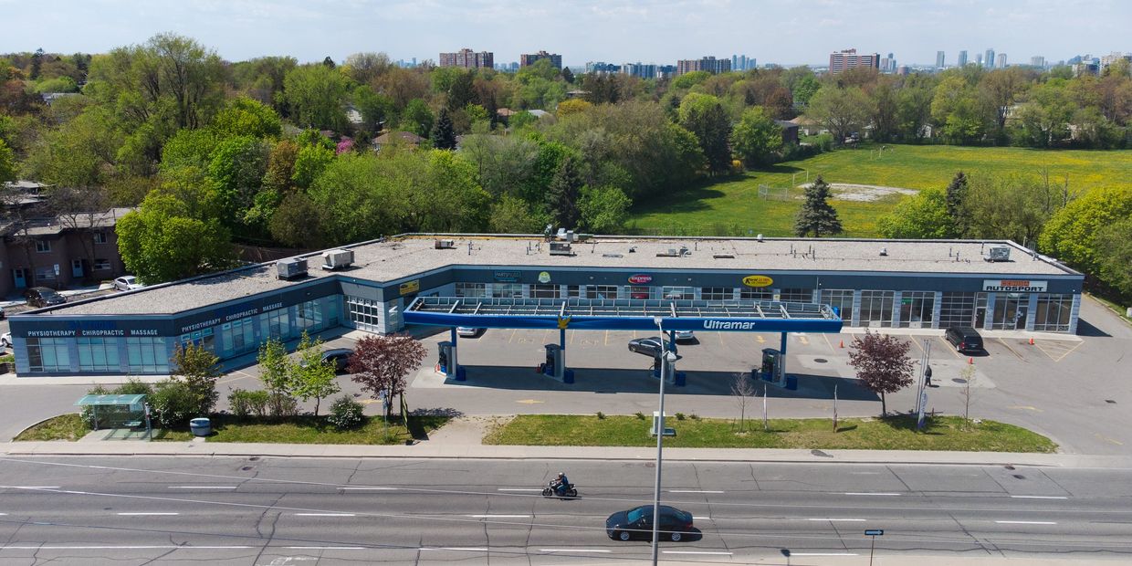 A gas station with shops in a suburban area under blue sky.