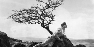 B&W image from Asquith's silent film 'A Cottage on Dartmoor', showing a man leaning against a rock.