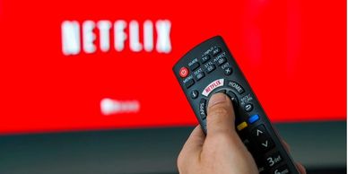 Image of a hand pointing a remote control at a television streaming Netflix