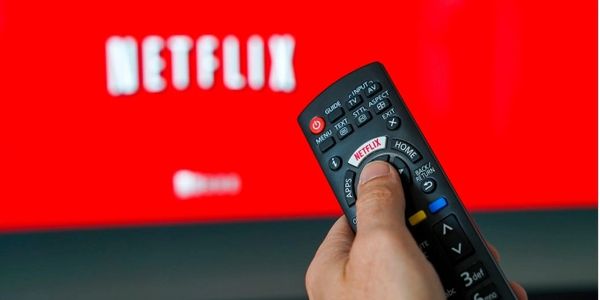 Image of a hand pointing a remote control at a television streaming Netflix