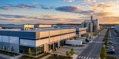 A modern industrial facility with loading docks and trucks at sunset.