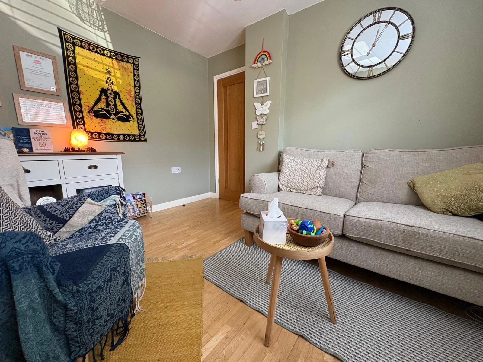 Cozy living room with sofa, armchair, and decorative wall tapestry.