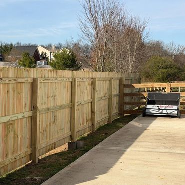 New wooden fence and patio area with outdoor equipment on a sunny day.