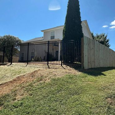 A house with a fenced yard on a sunny day under clear blue sky.