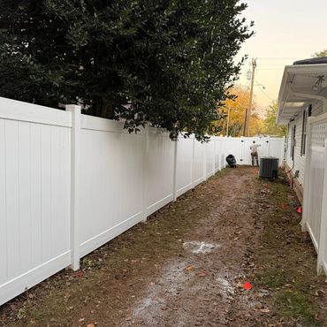 Long white vinyl fence alongside a house with a person working at the far end.