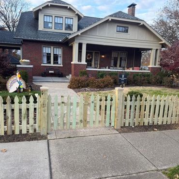 Cozy brick house with a welcoming front porch and white picket fence.