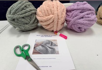Three large yarn balls and scissors on a table.