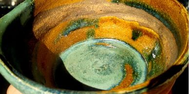 Close-up of a colorful ceramic bowl with a mix of green and orange glaze.