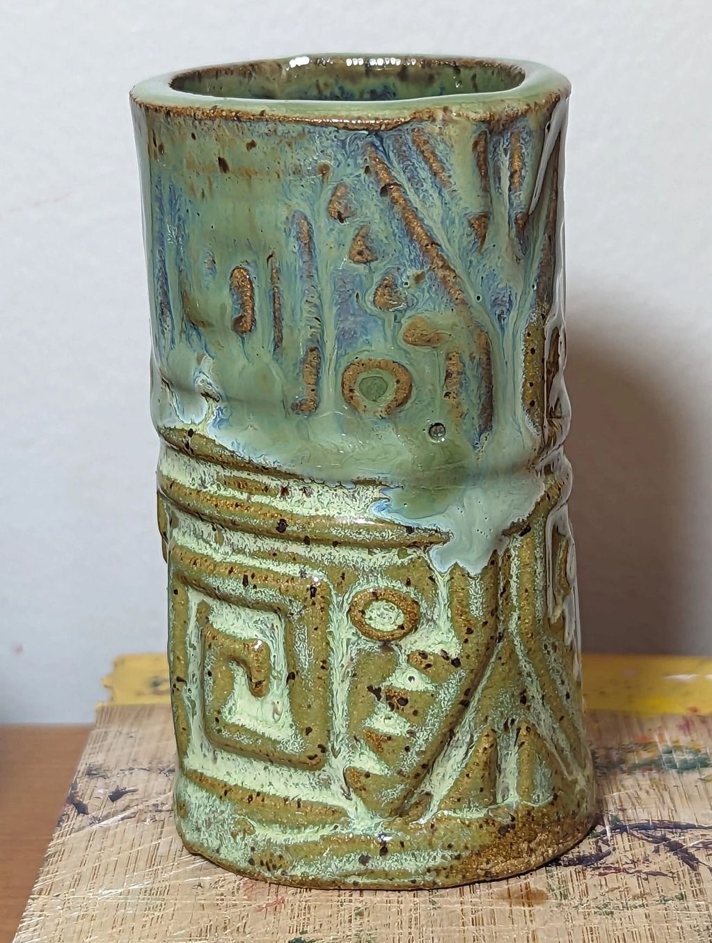 Slab built textured tall tumbler created by a teenager. Honey flux and sea weed glazes on speckled b