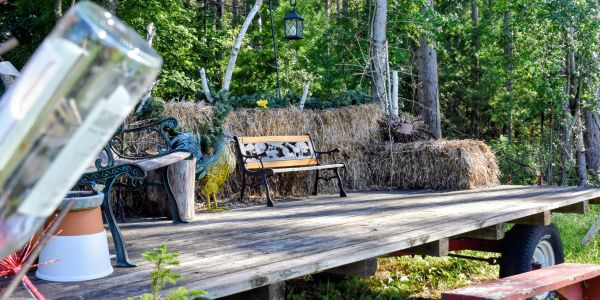 Outdoor wooden platform with benches and hay bales.