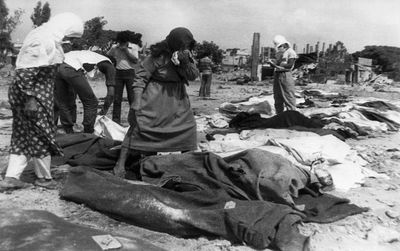 People searching among bodies in a disaster area.