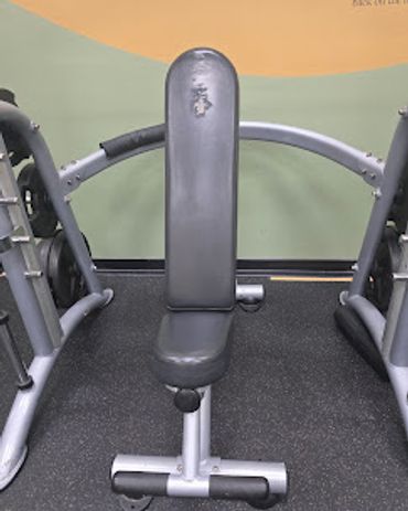 A worn black and silver gym bench for weightlifting exercises.