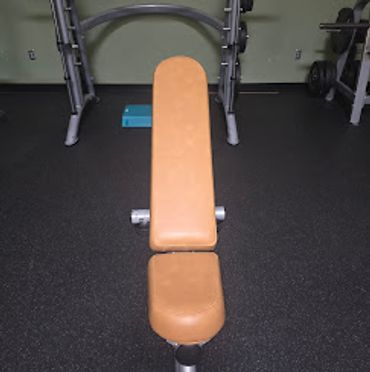 Brown padded workout bench in a gym.