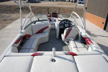 Interior view of a white and red motorboat with comfortable seating and steering console.