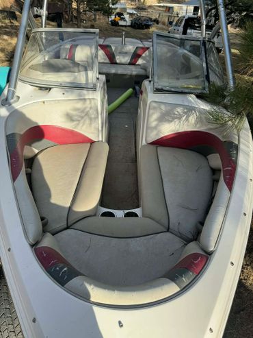 Interior seating area of a small motorboat with cushioned seats and cup holders.
