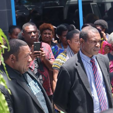 A group of people, some dressed formally, gathered outdoors.