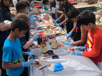 Kids preparing sandwiches under the guidance of adults 