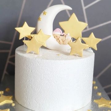 Baby laying on a moon cake topper with gold Stars 