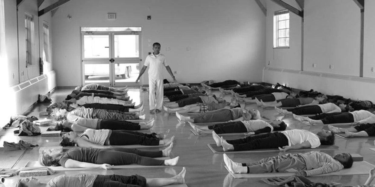 Group practicing yoga lying down in a spacious room with an instructor.