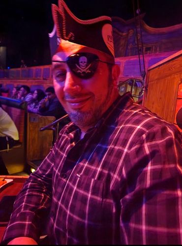 Man wearing a pirate hat and eyepatch at an event.