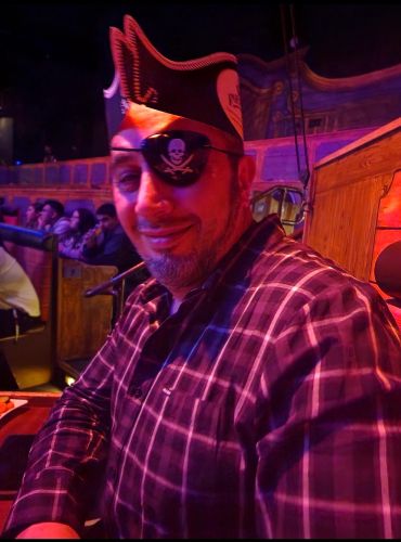 Man wearing a pirate hat and eyepatch at an event.